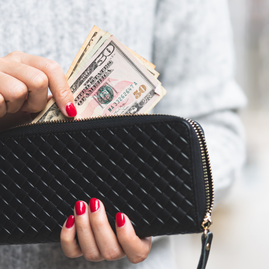 woman with red nails pulling money out of a black wallet