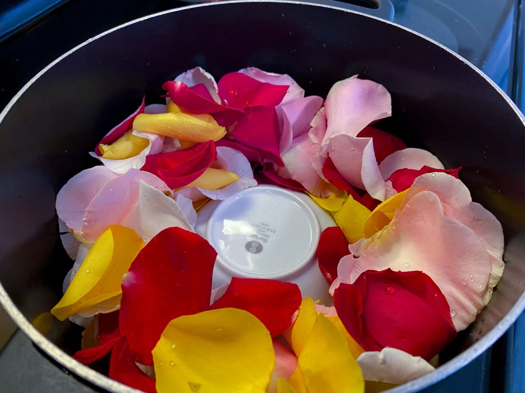 rose petals in a pot with a small glass dish
