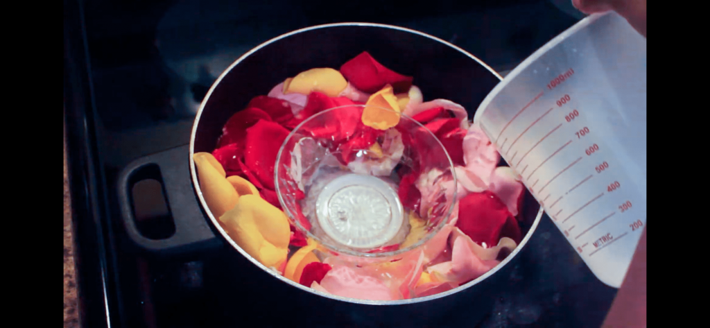 pouring distilled water into a pot filled with rose petals